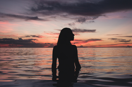 Young girl silhouette in sunset of koh phangan beach.の写真素材