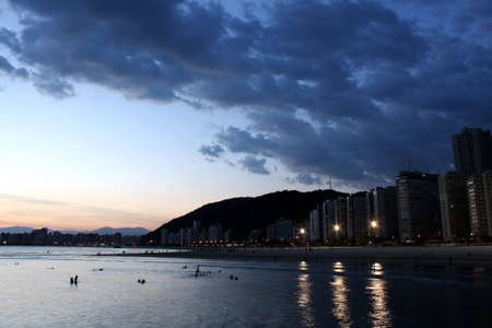 Beach of Itarare in Sao Vicente, Brazil. View from the rocks of Emissario Submarino in Santos, Brazil, to Sao Vicente. Showing people silhouettes playing in the water.の写真素材