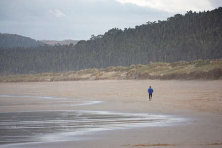 A man running alone on the beach watching a fantastic landscapeの写真素材