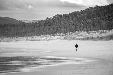 A man running alone on the beach watching a fantastic landscapeの写真素材