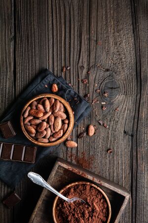 Healthy snack, superfood unroasted cocoa beans in a wooden bowl decorated with cacao powder with copy spaceの写真素材