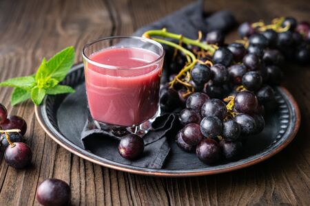 Seasonal homemade drink, freshly made grape juice in glass jar on rustic wooden backgroundの写真素材