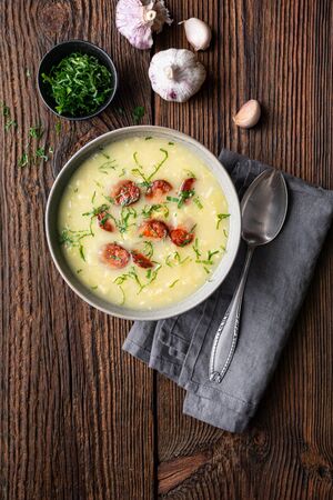 Caldo Verde soup made of savoy cabbage, pureed potatoes, onion, garlic and fried sausage slices in a ceramic bowl  on rustic wooden backgroundの写真素材