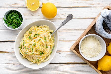 Pasta al Limone, delicious Italian meal, spaghetti with Parmesan, butter and lemon sauce, topped with fresh grated zest and cheese on rustic wooden backgroundの写真素材