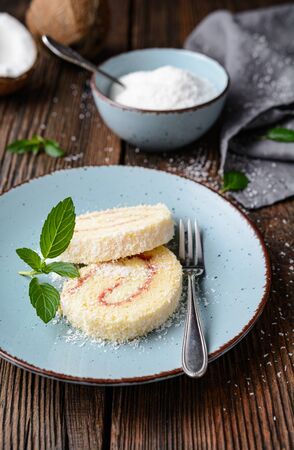 Delicious dessert, coconut roulade slices filled with vanilla and rum buttercream on rustic wooden backgroundの写真素材