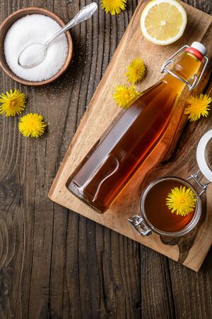 Homemade healthy dandelion syrup in a glass bottle, decorated with fresh flowers on rustic wooden backgroundの写真素材