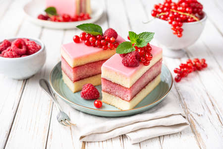 Delicious and refreshing juicy dessert, punch cake topped with sugar icing and fresh raspberries and...