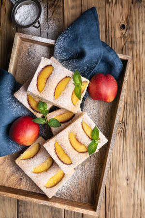 Bublanina, easy sponge cake with nectarine slices, dusted with powdered sugar on wooden backgroundの写真素材