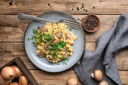 Nutritious scrambled eggs with mushrooms, onion and parsley for breakfastの写真素材