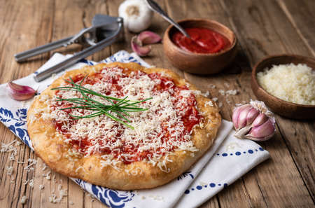 Classic Hungarian street food Langos, fried bread topped with ketchup, minced garlic and cheese on wooden backgroundの写真素材