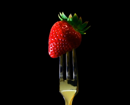 Strawberry with fork on black backgroundの写真素材