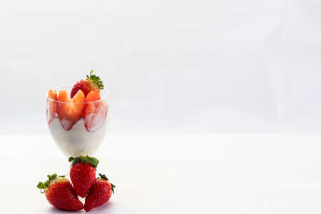 Strawberries with cream in a glass cup with strawberries lying on the base of the glassの写真素材