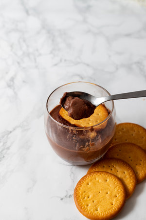 Glass with chocolate mousse with a spoon full of mousse and cookies