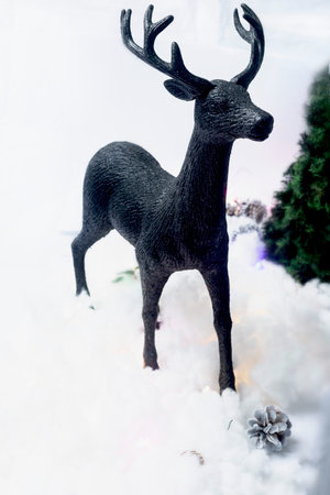 Christmas background with a black deer decoration, pine cones and bokeh lightsの写真素材