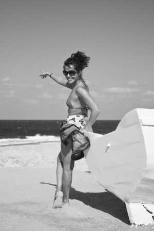 Women next to boat on the beach pointing to oceanの写真素材