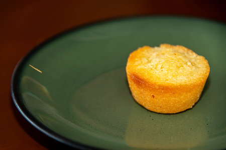A small, golden-brown pound cake served on a vibrant green plate. Simple, delicious, and perfect for a sweet bite.の写真素材