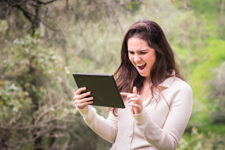 Young beautiful woman using a tablet computer at the park.の写真素材