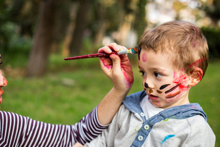 Happy mother painting her child´s face in the park.の写真素材