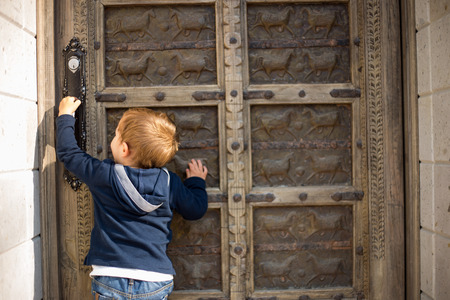 Cute little boy baby knocking on old door.の写真素材