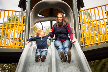 happy little boy child and mother mom on the playground slide.の写真素材