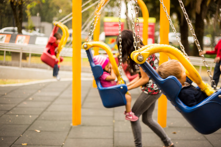 happy little boys childs on the playground swings.