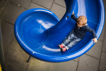 happy little boy on the playground slide.