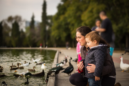 Picture of hugging mother and son in a lake with ducks.の写真素材