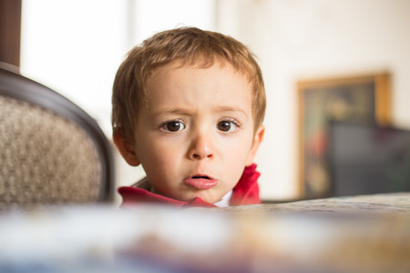 Offended little boy in the table.の写真素材