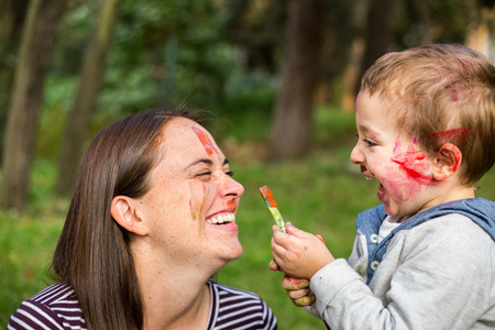 Happy child painting his mother´s face in the park.の写真素材