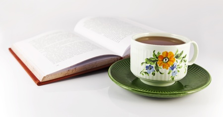 Open book and a cup of tea on a gray background.の写真素材