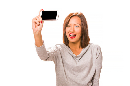 Beautiful happy young woman taking selfie using smartphone.の写真素材