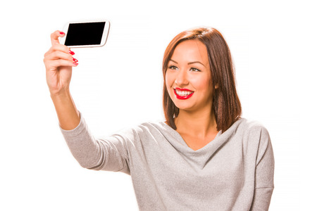 Beautiful happy young woman taking selfie using smartphone.の写真素材
