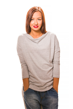 Beautiful happy young woman standing with hands in pockets, wearing jeans and grey blouse.の写真素材