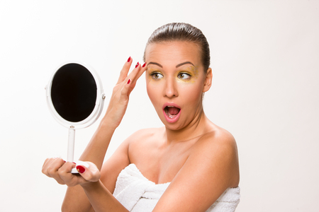 Gold make up. Brown sleek hair beautiful woman looking at mirror.の写真素材