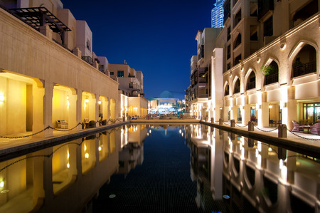 Colorful reflection of souk building in Downtown area during calm night. Calm water in hotel and restaurant pool. Dubai, United Arab Emirates.のeditorial素材