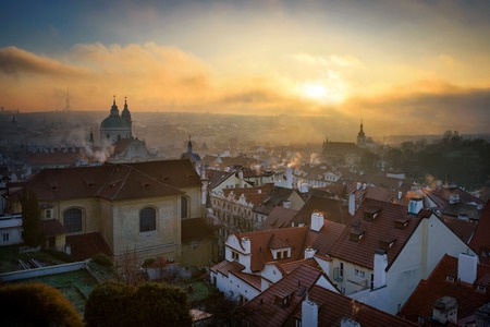 Foggy autumn morning. Misty Saint Nicolas church and Lesser town area. Colorful sunrise with clouds over old town. Prague, Czech republicの写真素材