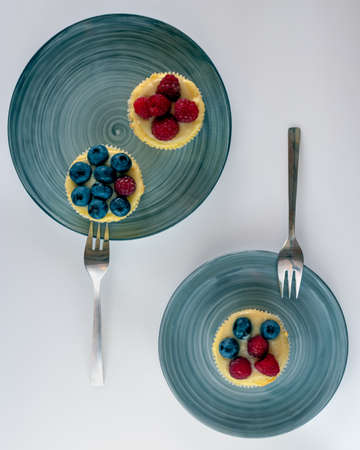 2 plates with swirly pattern with homemade wild fruits cupcakes and silver dessert forks.の写真素材