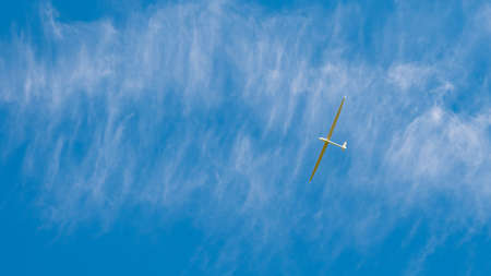 White glider aircraft hovering over the blue sky during delicately cloudy day.の写真素材