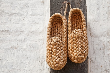 straw shoes are drying in the sun on the wall of the buildingの写真素材