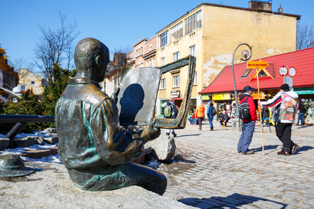 ZAKOPANE, POLAND - MARCH 09, 2015: Highlander sitting on a rock and reading a newspaper, made of bronze figure created to commemorate the 20th anniversary of the magazine Tygodnik Podhalanskiのeditorial素材
