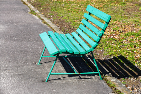 Wooden bench painted in green is placed along the path for pedestriansの写真素材