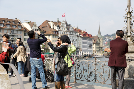 LUCERNE, SWITZERLAND - MAY 02, 2016: Unidentified tourists take pictures from the footbridge in the old town, that offers variety of sightseeing attractions.のeditorial素材