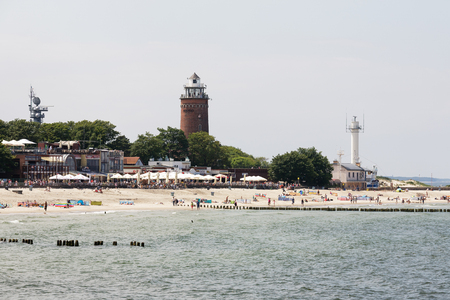 KOLOBRZEG, POLAND - JUNE 19, 2016: Sandy beach seen from the side of the Baltic Sea. The massive lighthouse that was built of brick dominates over the beachのeditorial素材