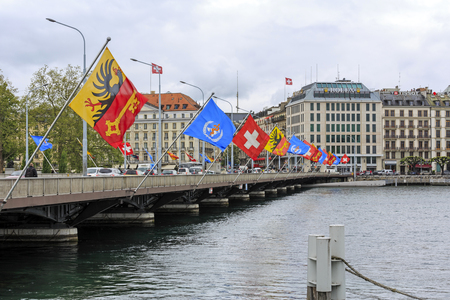 GENEVA, SWITZERLAND - MAY 21, 2013: Bridge over river Rodan decorated with various flags. City buildings can be seen in a distanceのeditorial素材
