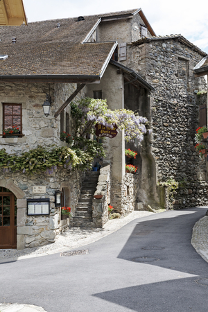 Yvoire, France - May 24, 2013: House and its stone stairs that lead to this medieval building is located by narrow street. The front wall of the building is decorated with various plants and flowersのeditorial素材
