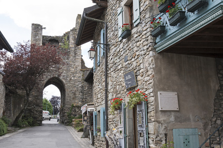 Yvoire, France - May 24, 2013: Narrow street leads through a gate in the damaged tower. Townhouses which were built of stone can be seen in this medieval town.のeditorial素材