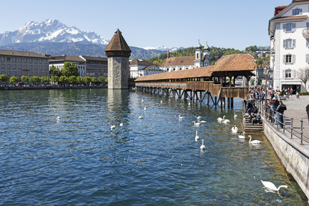 Lucerne, Switzerland - May 05, 2016: Octagonal tower and the Roofed Chapel Bridge by the River Reuss and Jesuit church and Peak of Pilatus are four widely known landmarks in the cityのeditorial素材