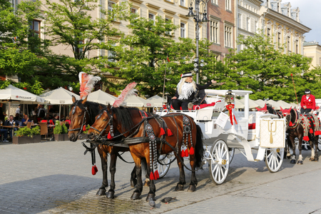 Krakow, Poland - May 25, 2017: Stylized horse-drawn carriages stopped on the market square and these vehicles are available to hire for tourists wishing to have sightseeing the city during the rideのeditorial素材