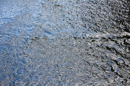 The water of the flowing river is very dark despite the sunny dayの写真素材