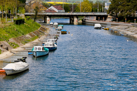 Yverdon-les-Bains, Switzerland - 18 April 2017: Boats moored at piers along the river bank. The railway bridge can be seen in the distanceのeditorial素材